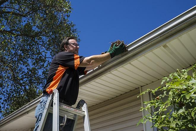 a roofer repairing a damaged gutter on a house in Beacon, NY